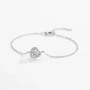 Sterling silver bracelet with heart-shaped gemstone center and delicate chain on white background.