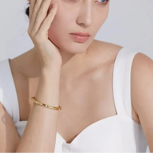 Woman in white top wearing gold-plated 925 silver bracelet with small gemstones