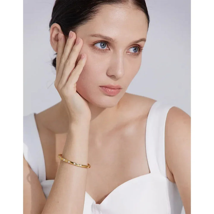 Woman in white top wearing gold-plated 925 silver bracelet with small gemstones