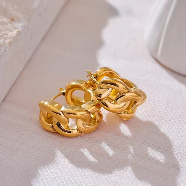 Pair of gold hoop earrings on a light background.