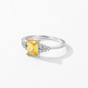 Silver ring with a yellow gemstone on a white background