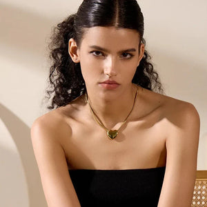 Woman wearing a black strapless top and gold necklace with a heart pendant.