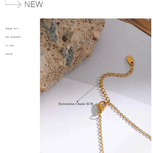 Gold extension chain on a white surface with text indicating its length.