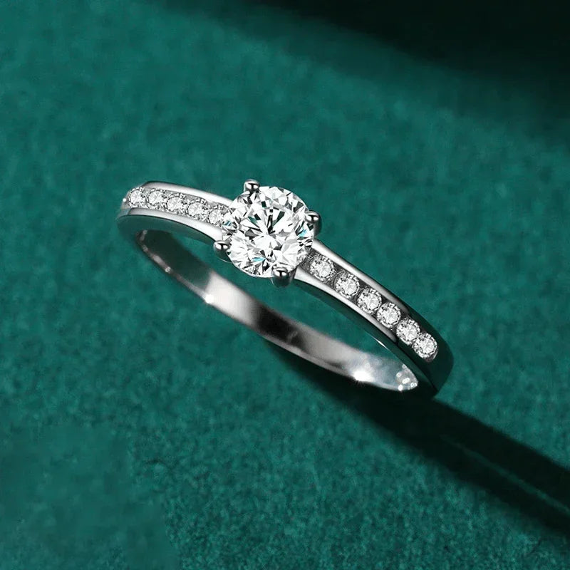 Elegant silver engagement ring with round center stone and pavé setting on green background