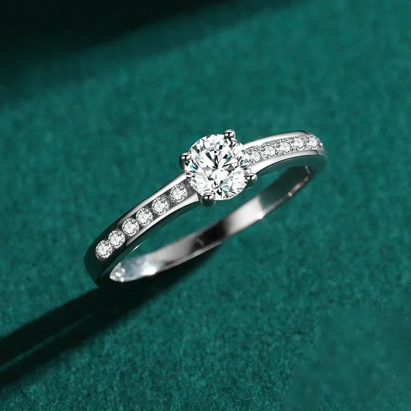 Sterling silver ring with round center stone and pavé side stones on green background