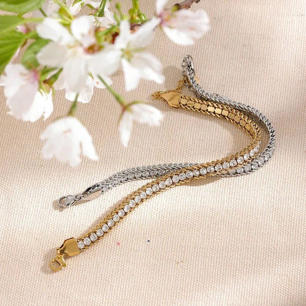 Gold and silver bracelet on a beige surface with cherry blossoms