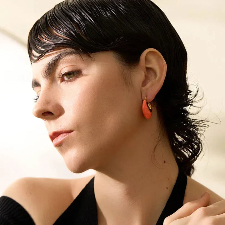 Woman wearing orange earrings with a neutral background