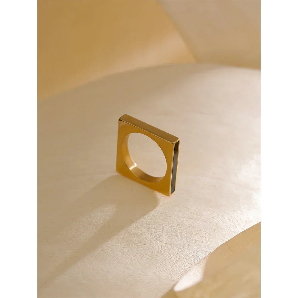 Square gold-plated ring with minimalist design on a neutral background