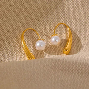 Gold hoop earrings with pearls on a beige background