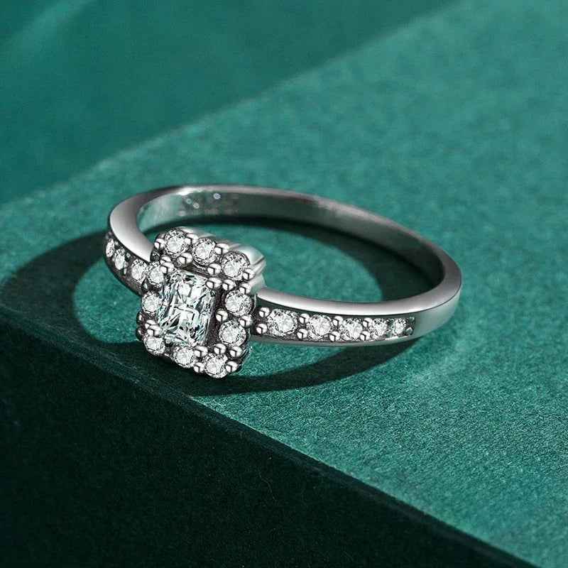 925 silver ring with rectangular center stone and pavé cubic zirconia accents on a green background