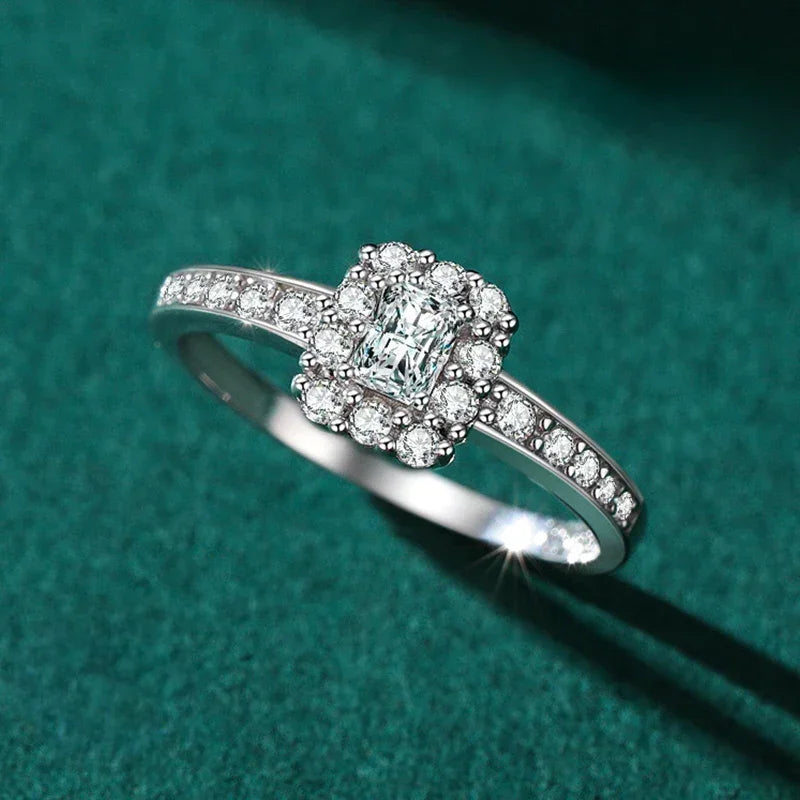 925 silver halo engagement ring with emerald-cut and round white stones on green background