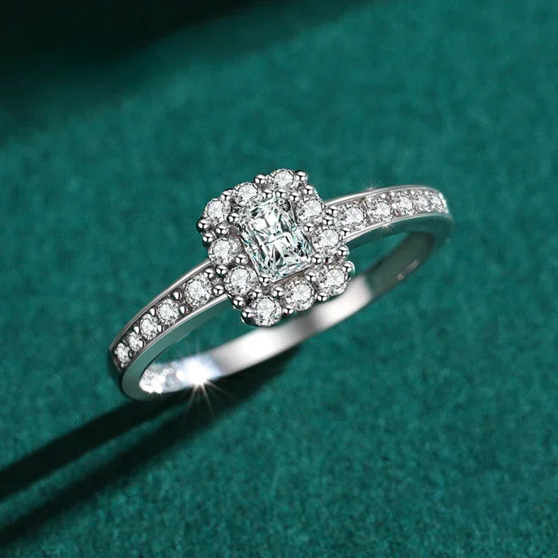 Elegant silver halo engagement ring with rectangular center stone and pavé diamonds on green background