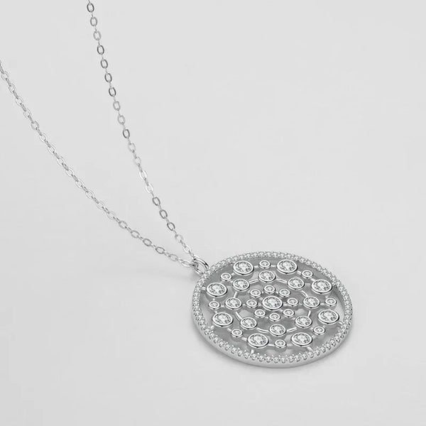 Silver necklace with a round, diamond-studded pendant on a light gray background