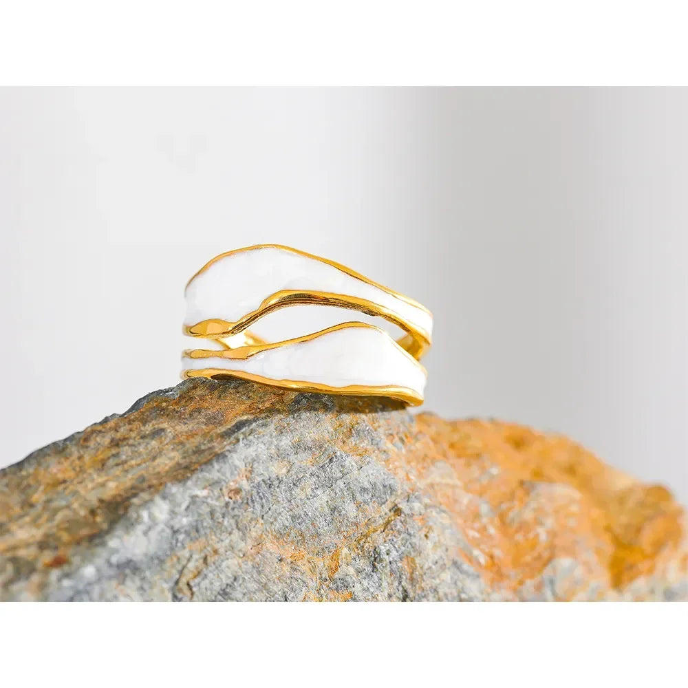 Gold-plated abstract silver ring with white enamel on a textured rock