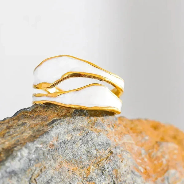 Gold-plated abstract silver ring with white enamel on a textured rock