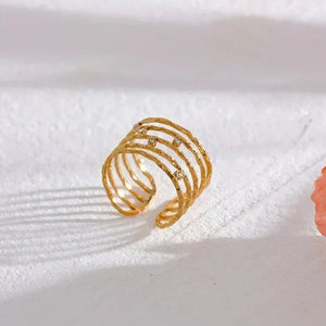 18K gold-plated open ring with textured bands and small clear stones on a white surface
