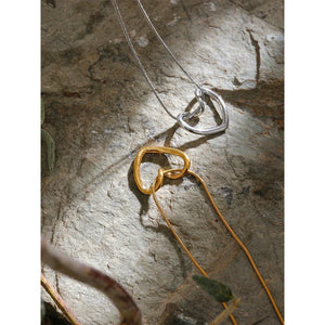 Gold and silver heart-shaped pendant necklaces on textured stone surface