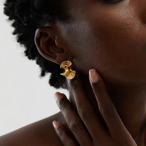 Gold earring worn by a person with a neutral background
