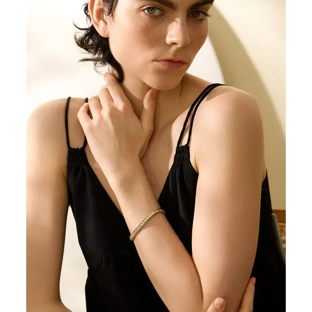 Woman wearing a gold-plated silver bracelet, styled with a black sleeveless top