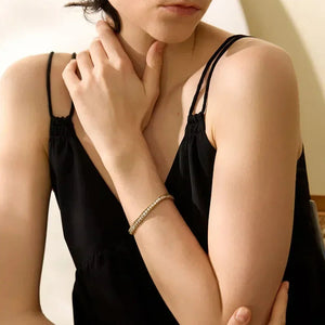Woman wearing a gold-plated silver bracelet, styled with a black sleeveless top