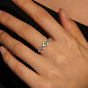 Close-up of a hand wearing a ring with a green gemstone on a neutral -background-TM & CO. JEWELS 