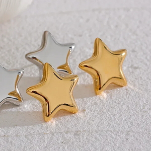 Star-shaped earrings in gold and silver on a textured surface