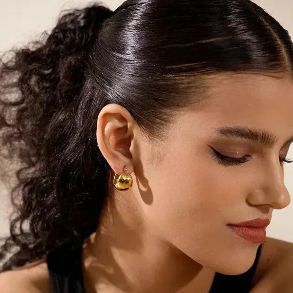 Woman wearing elegant 18K gold-plated chunky hoop earrings with a black top