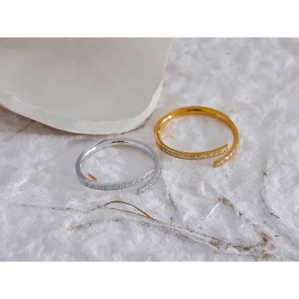 Gold and silver adjustable open rings with pavé stones on a soft white surface