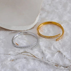 Gold and silver adjustable open rings with pavé stones on a soft white surface