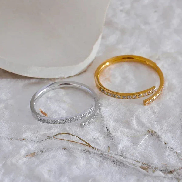 Gold and silver adjustable open rings with pavé stones on a soft white surface