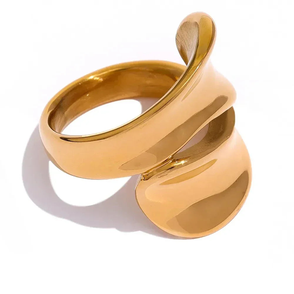 Abstract gold-plated ring with smooth, sculptural curves on a white background