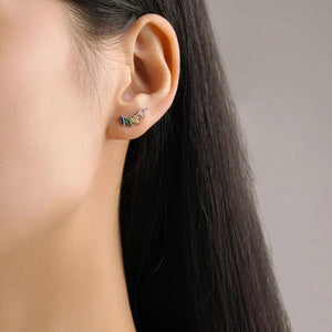 Close-up of an ear wearing a small earring with a neutral background