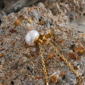Gold-plated necklace with pearl and crystal pendant on textured stone, elegant everyday jewelry