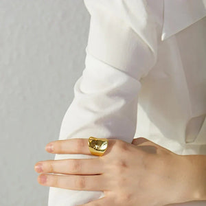 Woman wearing chunky gold-plated statement ring on hand, elegant jewelry close-up