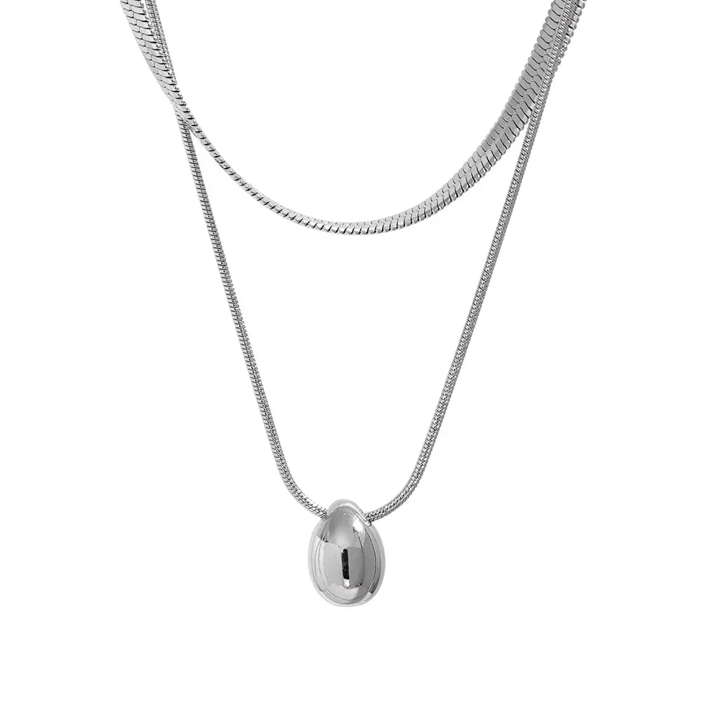 Layered sterling silver chain necklace with sleek oval pendant on white background