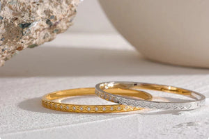 Two gold rings on a textured surface with a neutral background