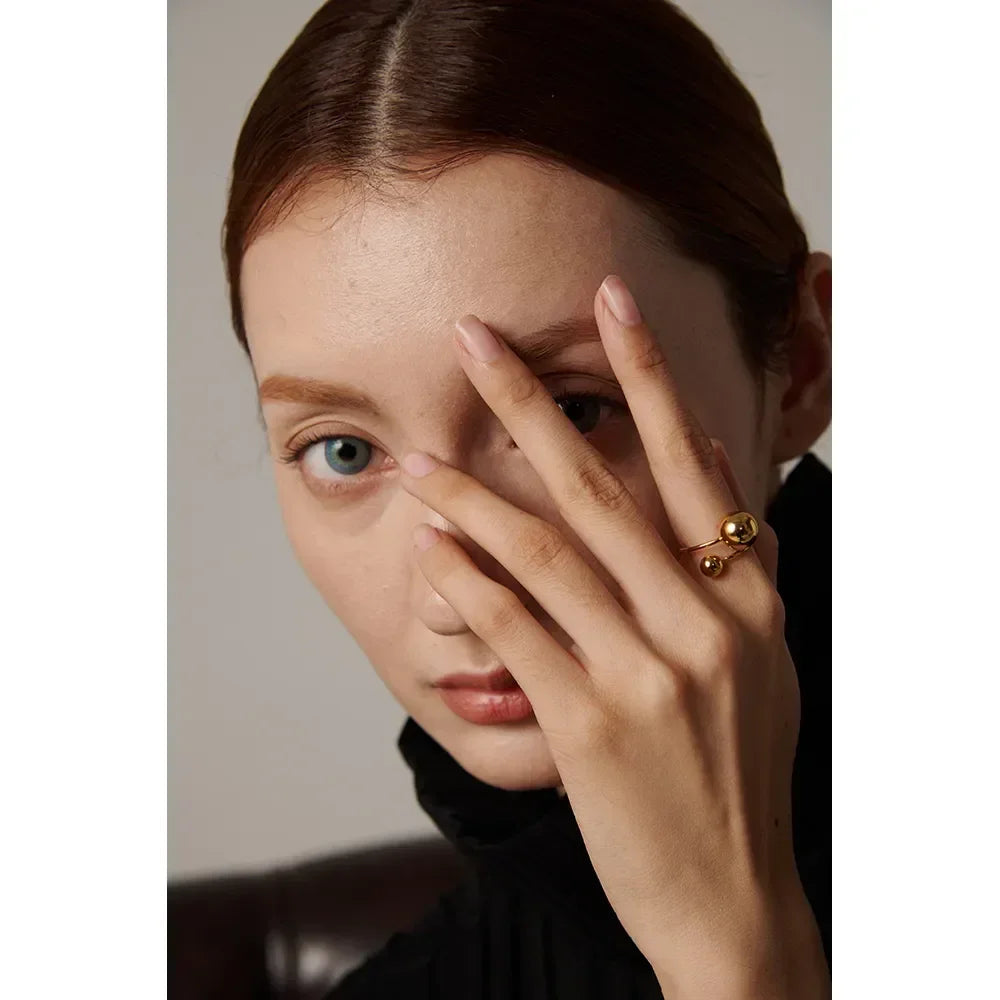 Woman wearing a modern gold-plated statement ring with spherical accents.