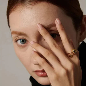 Woman wearing a modern gold-plated statement ring with spherical accents.
