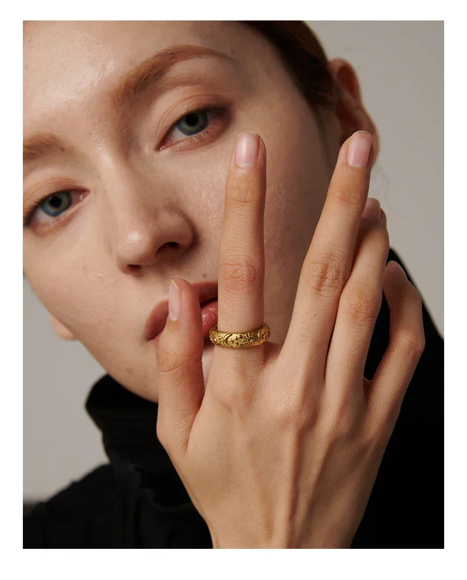 woman wearing engraved gold-plated statement ring on finger, close-up jewelry shot