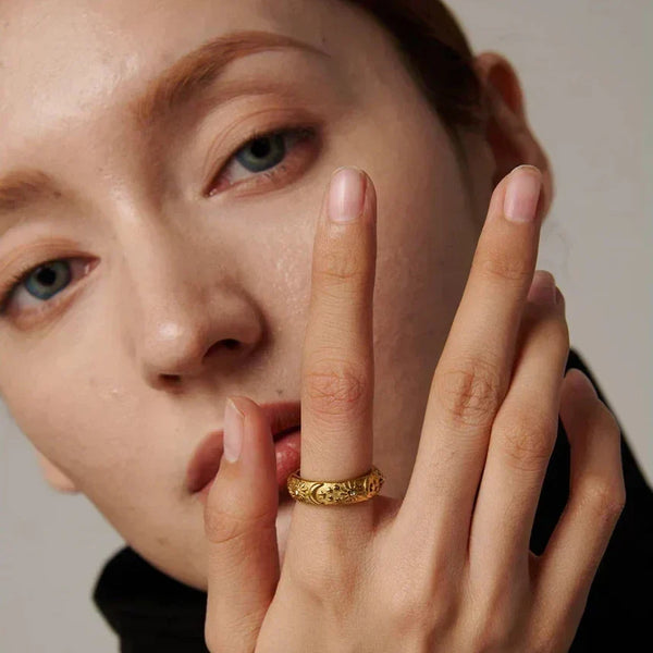 woman wearing engraved gold-plated statement ring on finger, close-up jewelry shot