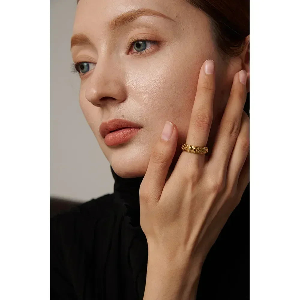 Woman wearing a textured gold-plated ring on her finger, showcasing elegant jewelry style