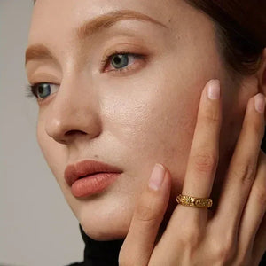 Woman wearing a textured gold-plated ring on her finger, showcasing elegant jewelry style