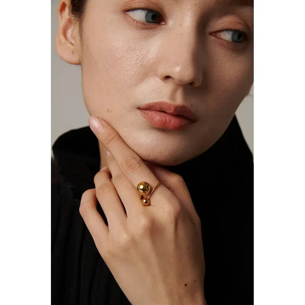 Woman wearing a modern 18K gold-plated silver ring with two spherical accents.