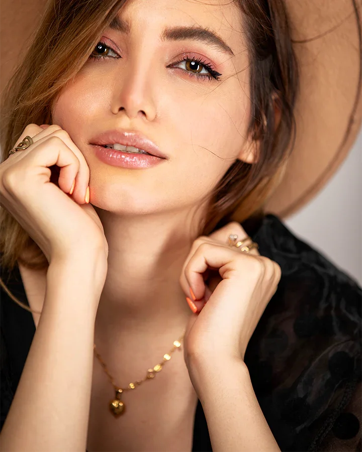 Woman wearing a gold necklace with a plain background