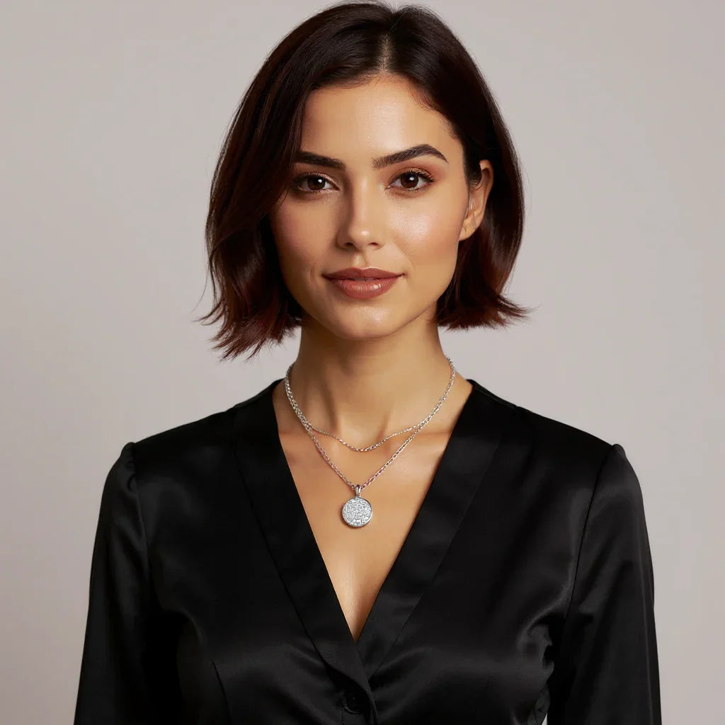 Woman wearing a black satin top and multiple necklaces against a neutral background