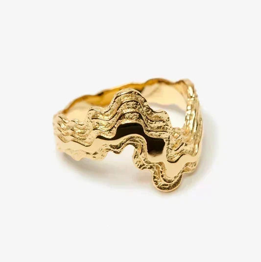 Gold ring with wavy design on a white background