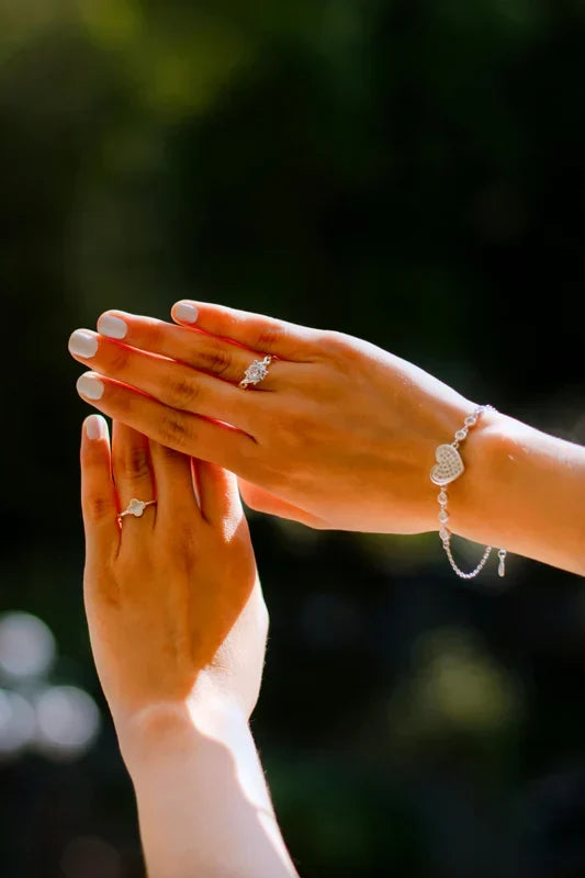A quality-crafted, delicate heart-accented bracelet and ring set from the TM & Co. Jewels collection, elegantly displayed on a model's hands.